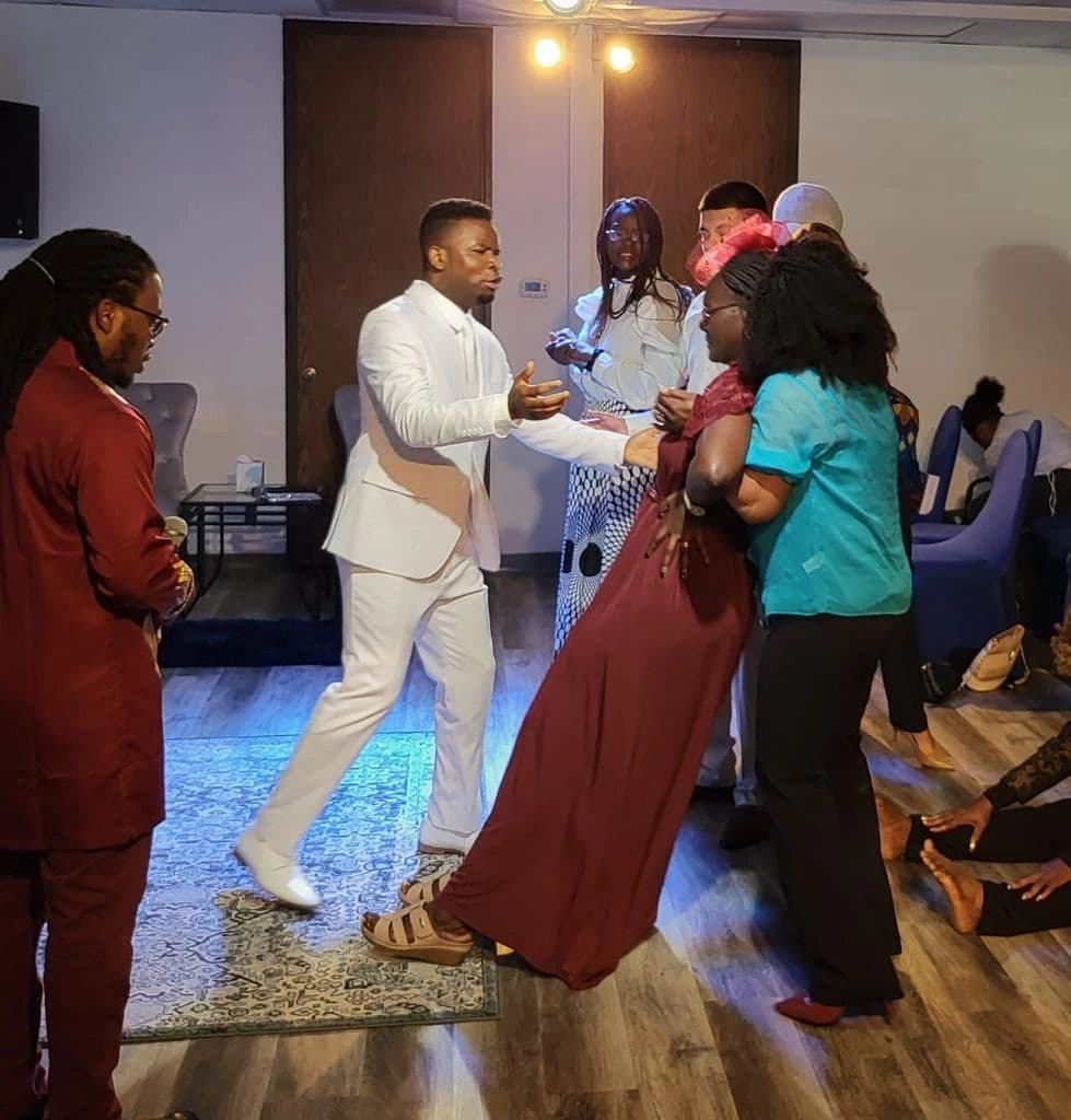 Pastor Tare Godfrey praying for someone during a church gathering